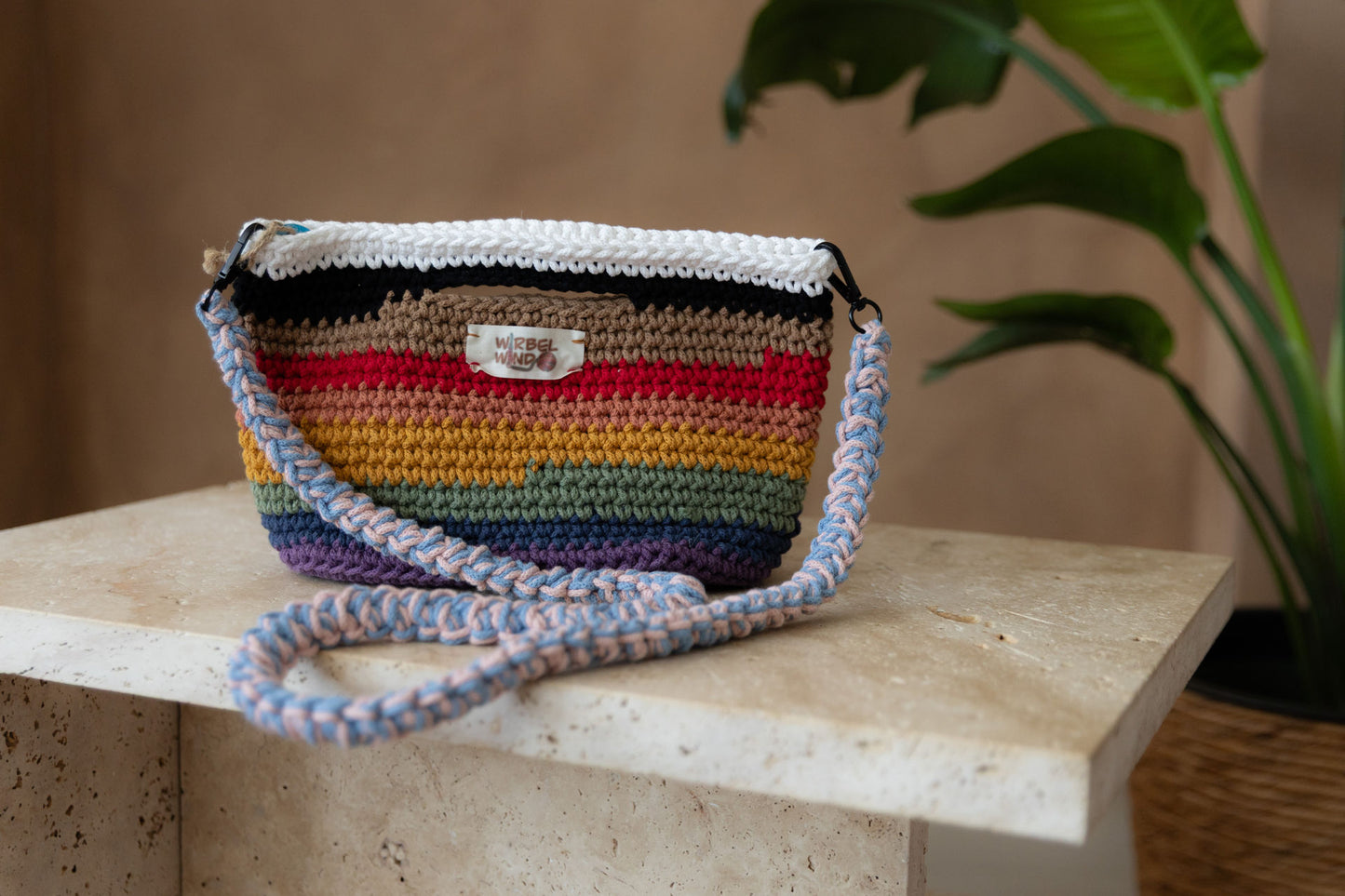 Nahaufnahme des vorangegangenen Bildes. Die Tasche und der Tisch sind scharf, der Hintergrund ist unscharf. Wir sehen deutlich das Muster und das Garn der Tasche.