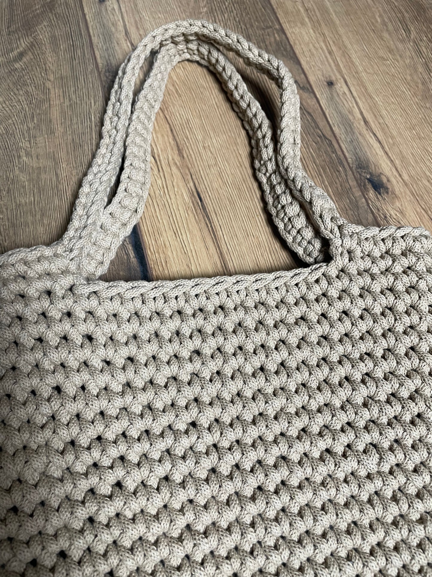 Nahaufnahme der FLORA Häkeltasche in sandbeiger Farbe. Das Bild zeigt deutlich die einzelnen Häkelmaschen und die Struktur des recycelten Baumwollgarns. Die handwerkliche Qualität und das gleichmäßige Maschenbild der Handarbeit sind gut erkennbar.