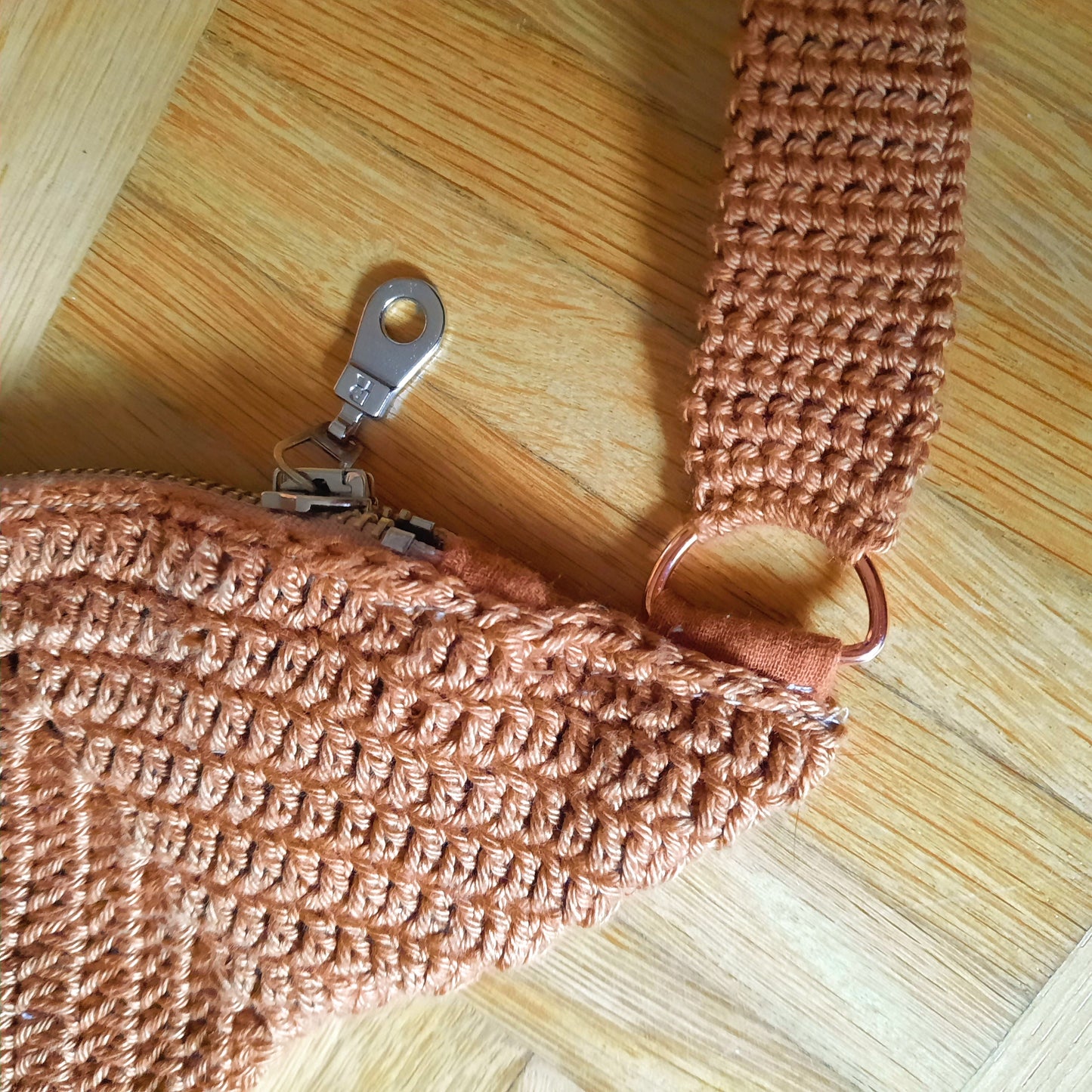 Nahaufnahme auf eine Ecke der Tasche, der Reißverschluss und die roséfarbene Hardware sind klar zu sehen.