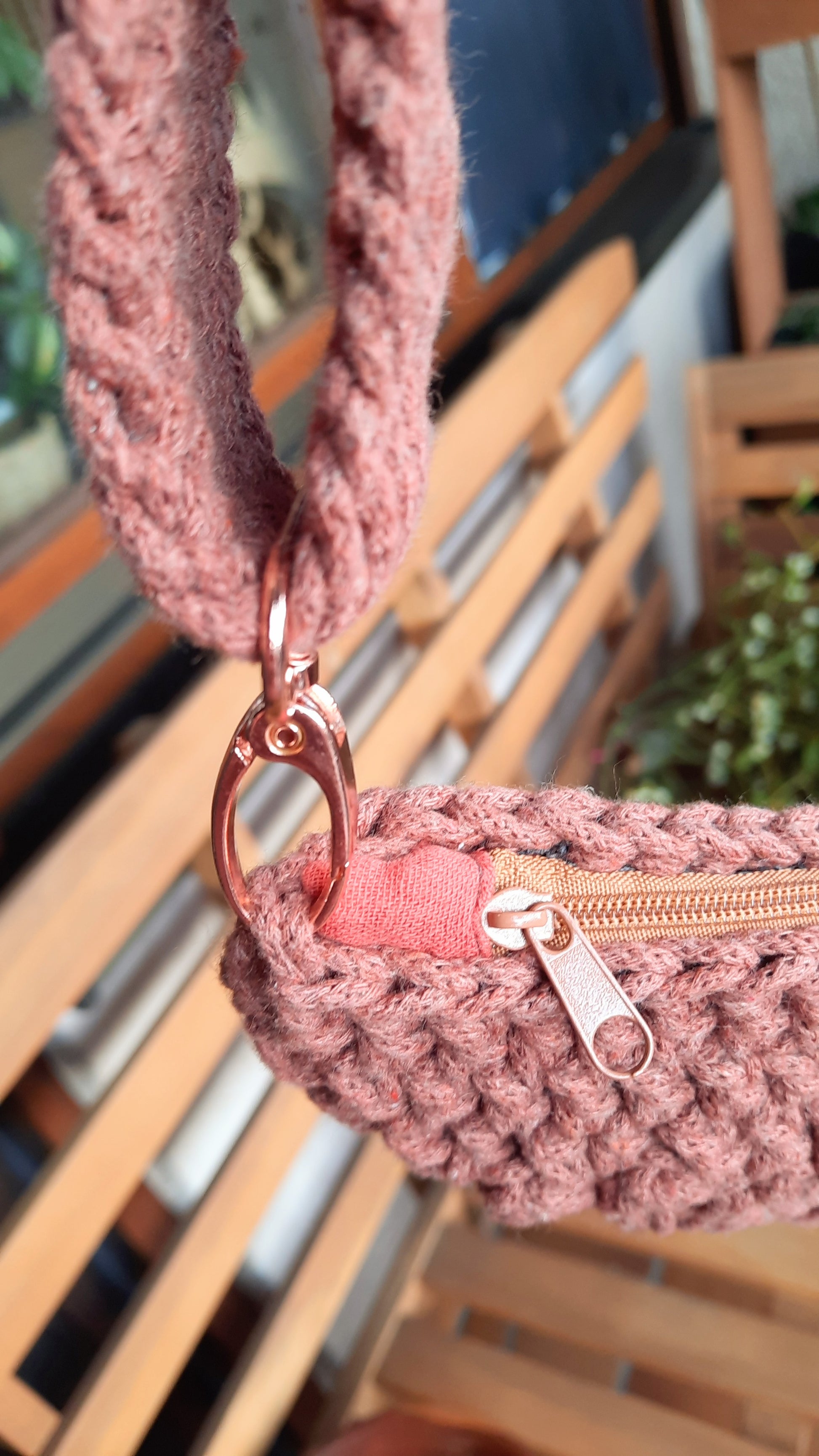 Nahaufnahme der roséfarbenen Hardware (Karabiner), sowie des champagnerfarbenen Reißverschlusses.