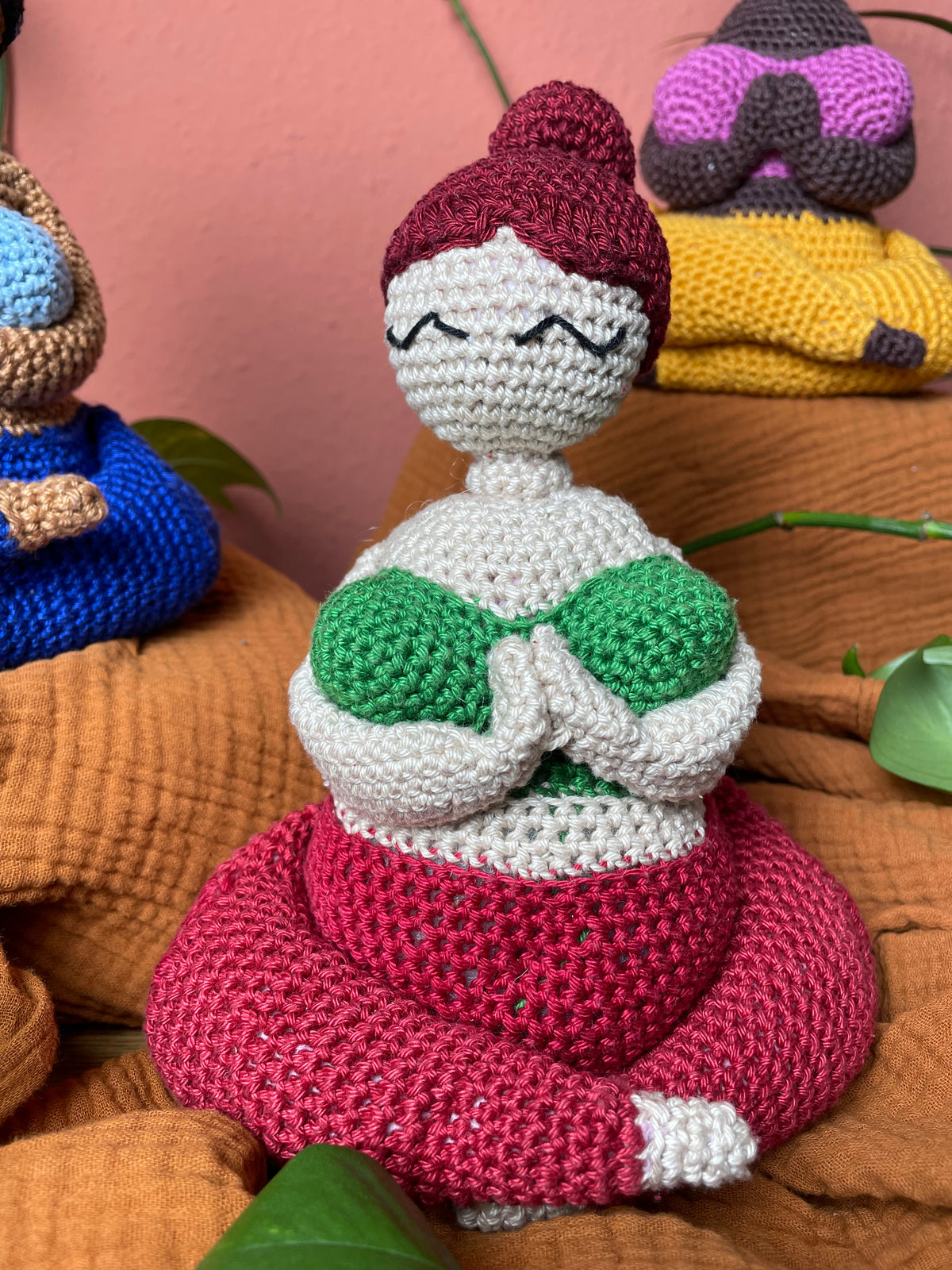 Gehäkelte Yoga Figur: Kurvig, weiblich, dunkelroter Dutt, helle Haut, grünes Top, rote Hose