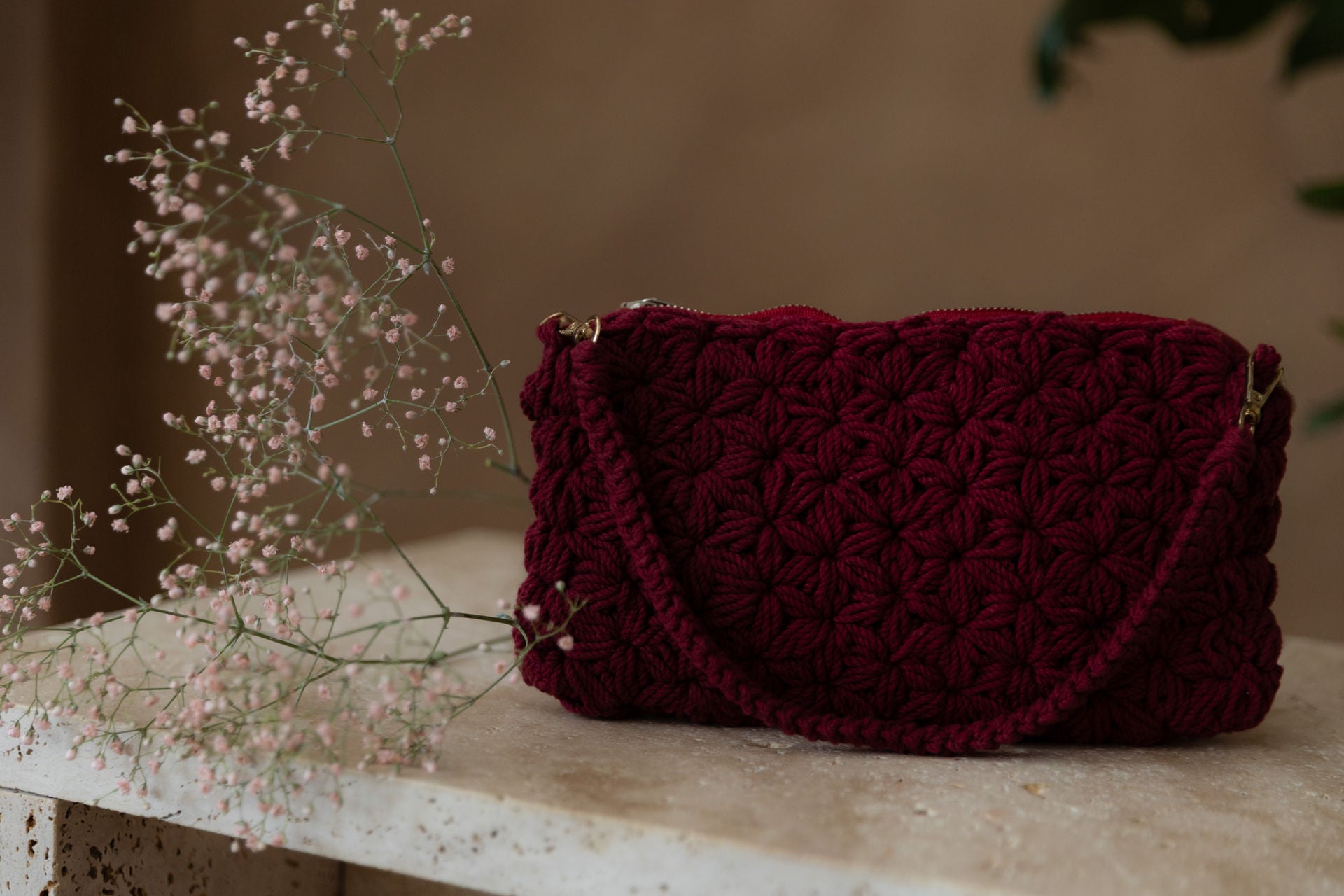 Nahaufnahme des vorangegangenen Bildes. Die Tasche und das Schleierkraut sind scharf, der Hintergrund ist unscharf. Wir sehen deutlich das Muster, das aussieht wie viele kleine Blumen.
