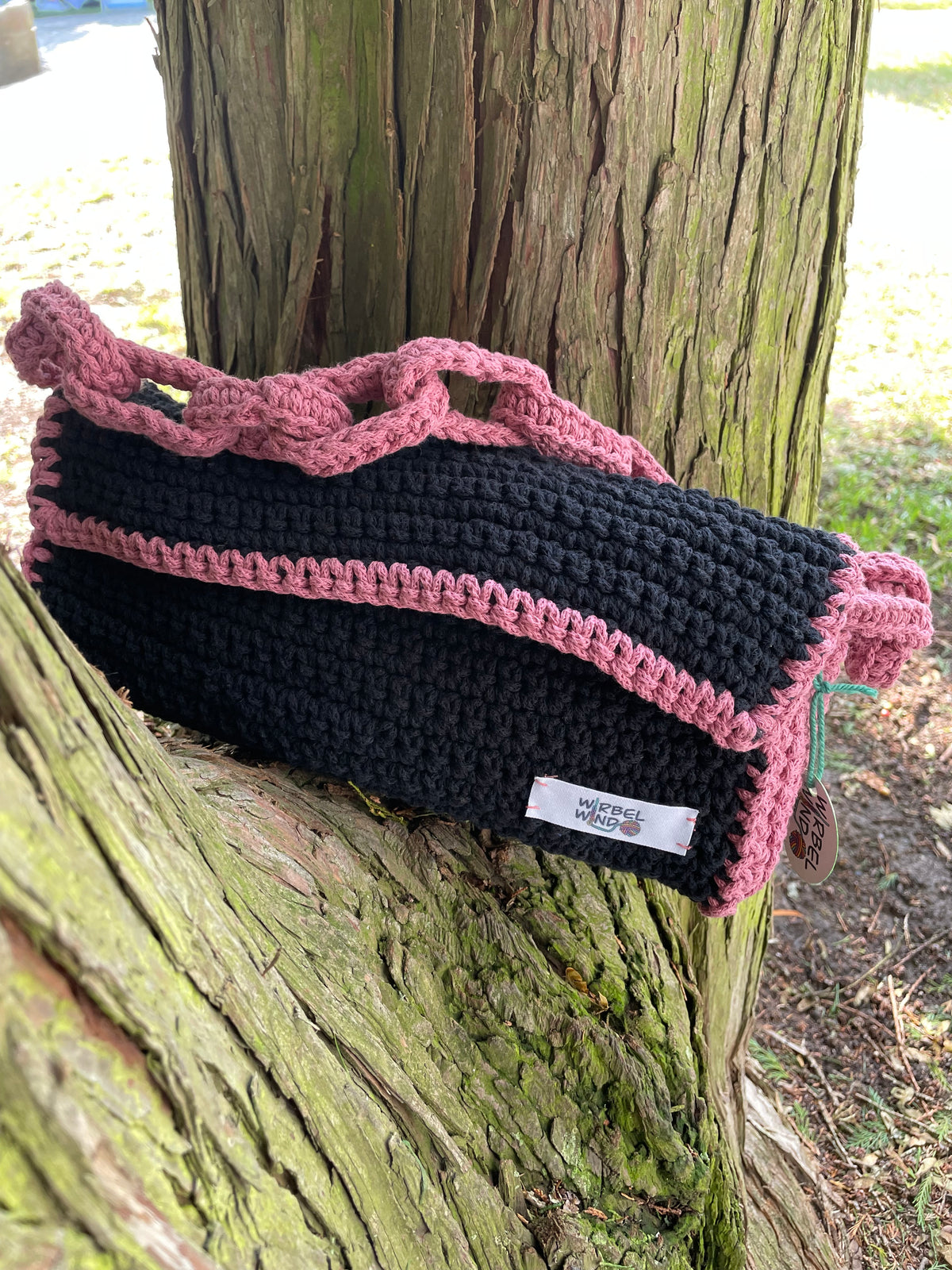 Die Tasche steht auf der Astabzweigung eines Baumes, der Henkel liegt oben auf der Tasche.