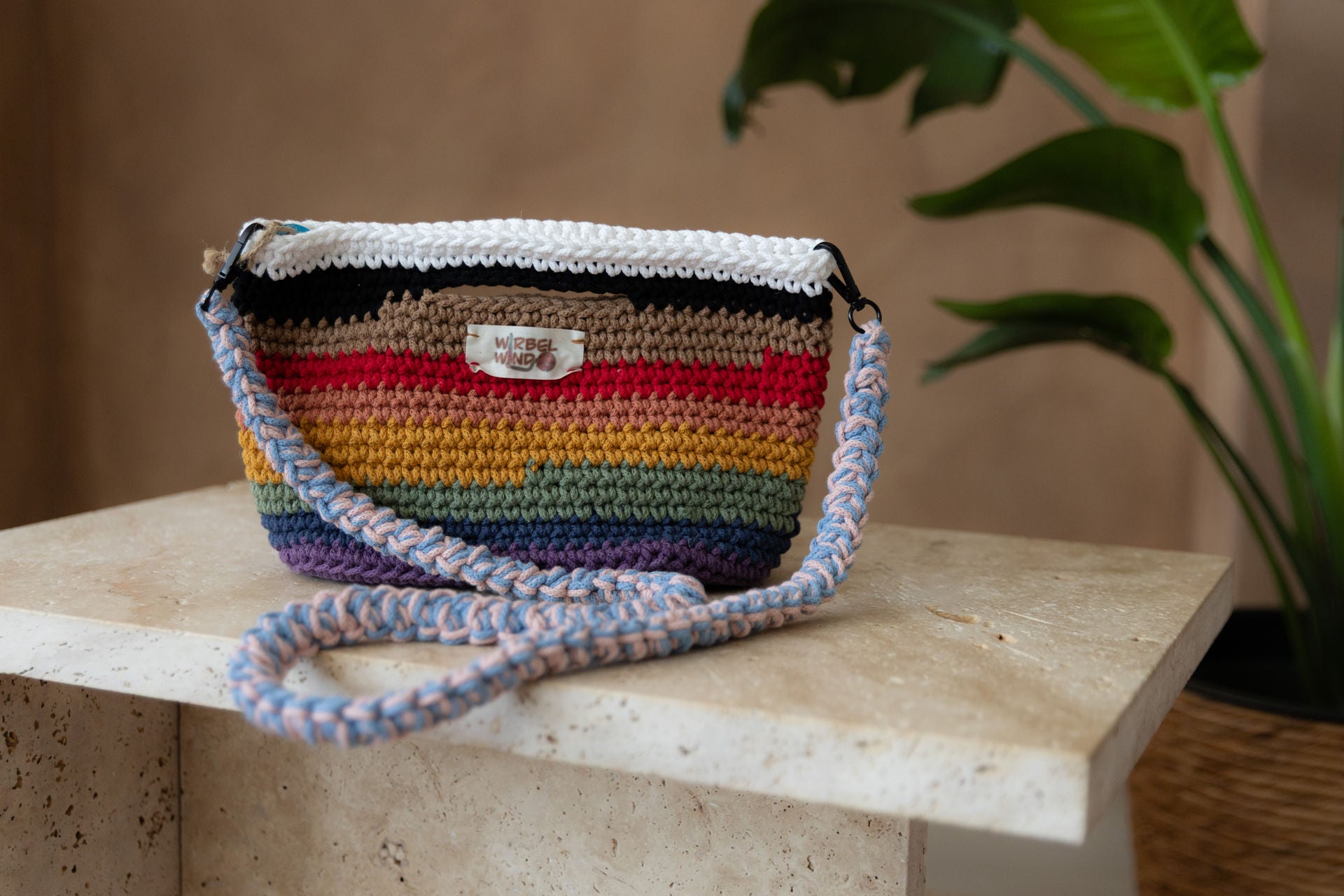 Nahaufnahme des vorangegangenen Bildes. Die Tasche und der Tisch sind scharf, der Hintergrund ist unscharf. Wir sehen deutlich das Muster und das Garn der Tasche.