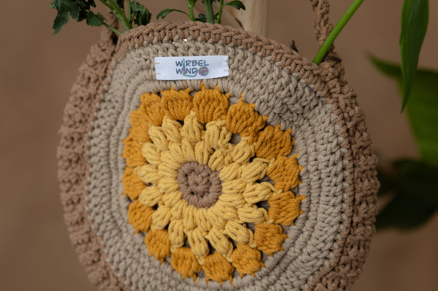 Noch nähere Aufnahme der Sonnenblume in der MItte der Tasche. Wir sehen deutlich das Garn und das Muster. Die Stängel der Blum en sind am oberen Bildrand zu sehen.