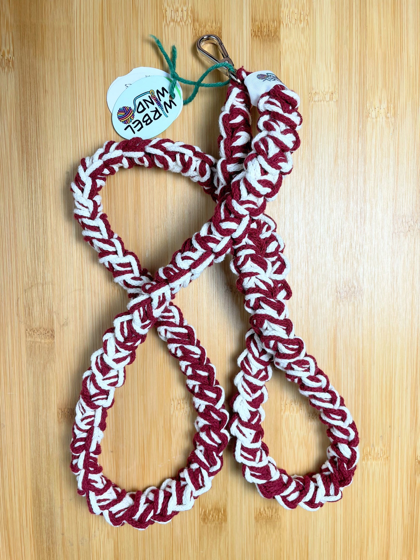  Weiß-Weinrot-meliertes Lanyard kringelt sich. Wirbelwindlogo am unteren Ende, direkt über silbernem Karabiner angenäht.