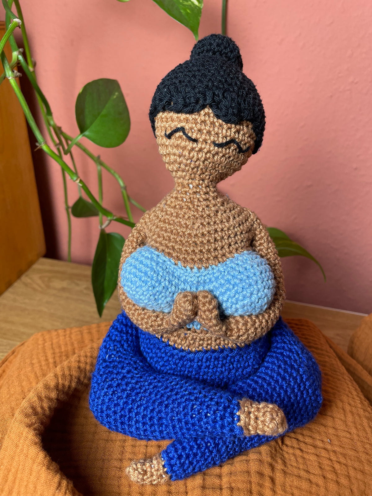 Gehäkelte Yoga Figur: schwarzer Dutt, hellbraune Haut, hellblaues Top, dunkelblaue Hose