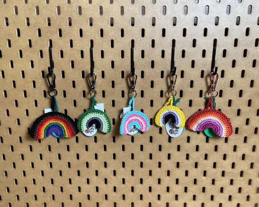 5 Der Regenbogen-Schlüsselanhänger hängen an einem Lochboard nebeneinander (von links nach rechts): Philadelphia Pride Flagge, Aromantische Pride Flagge, Trans Pride Flagge, Nonbinary Pride Flagge, Lesbische Pride Flagge.