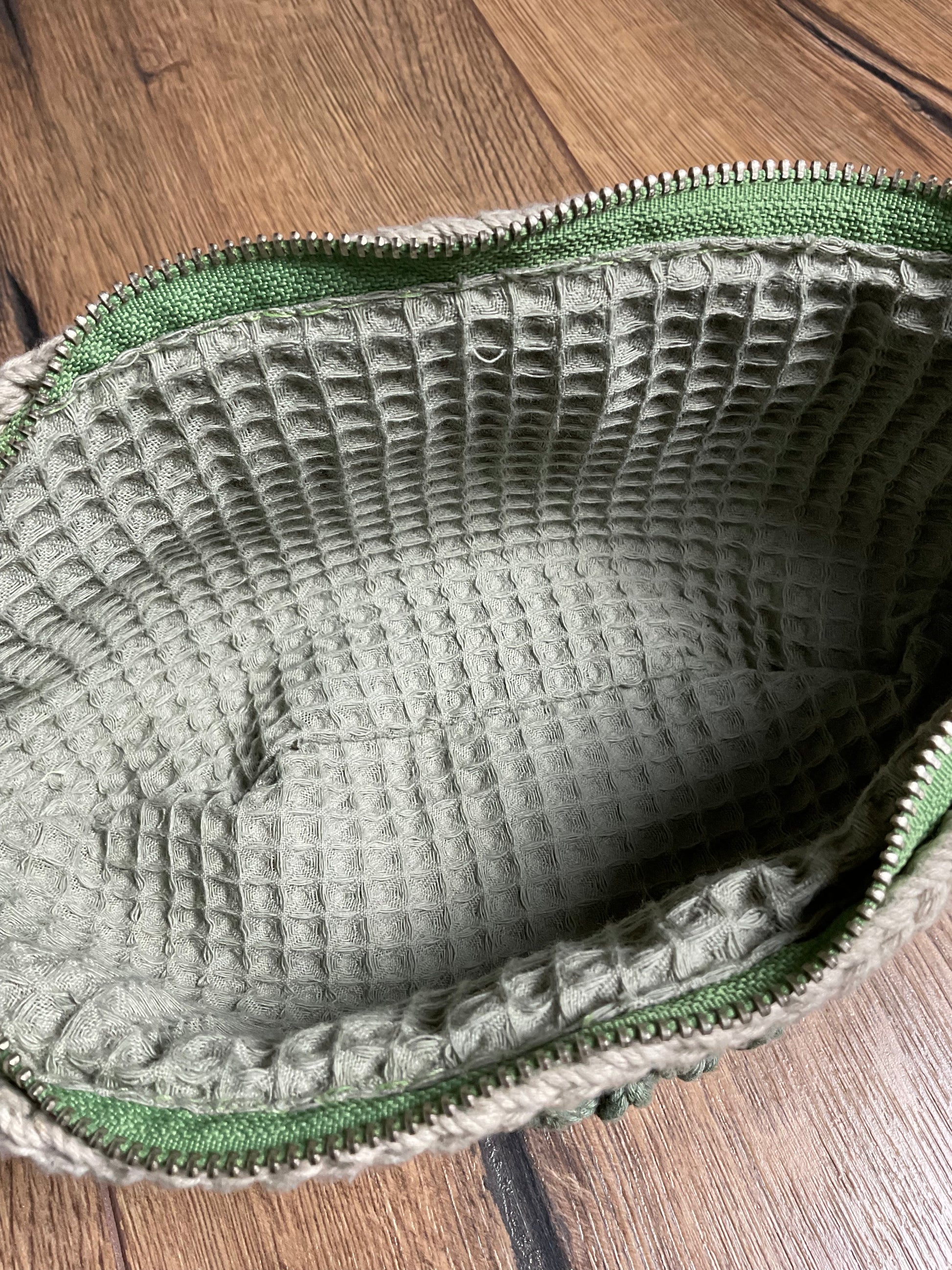 Nahaufnahme der geöffneten Tasche auf das salbeifarbene Innenfutter aus Waffelstoff.