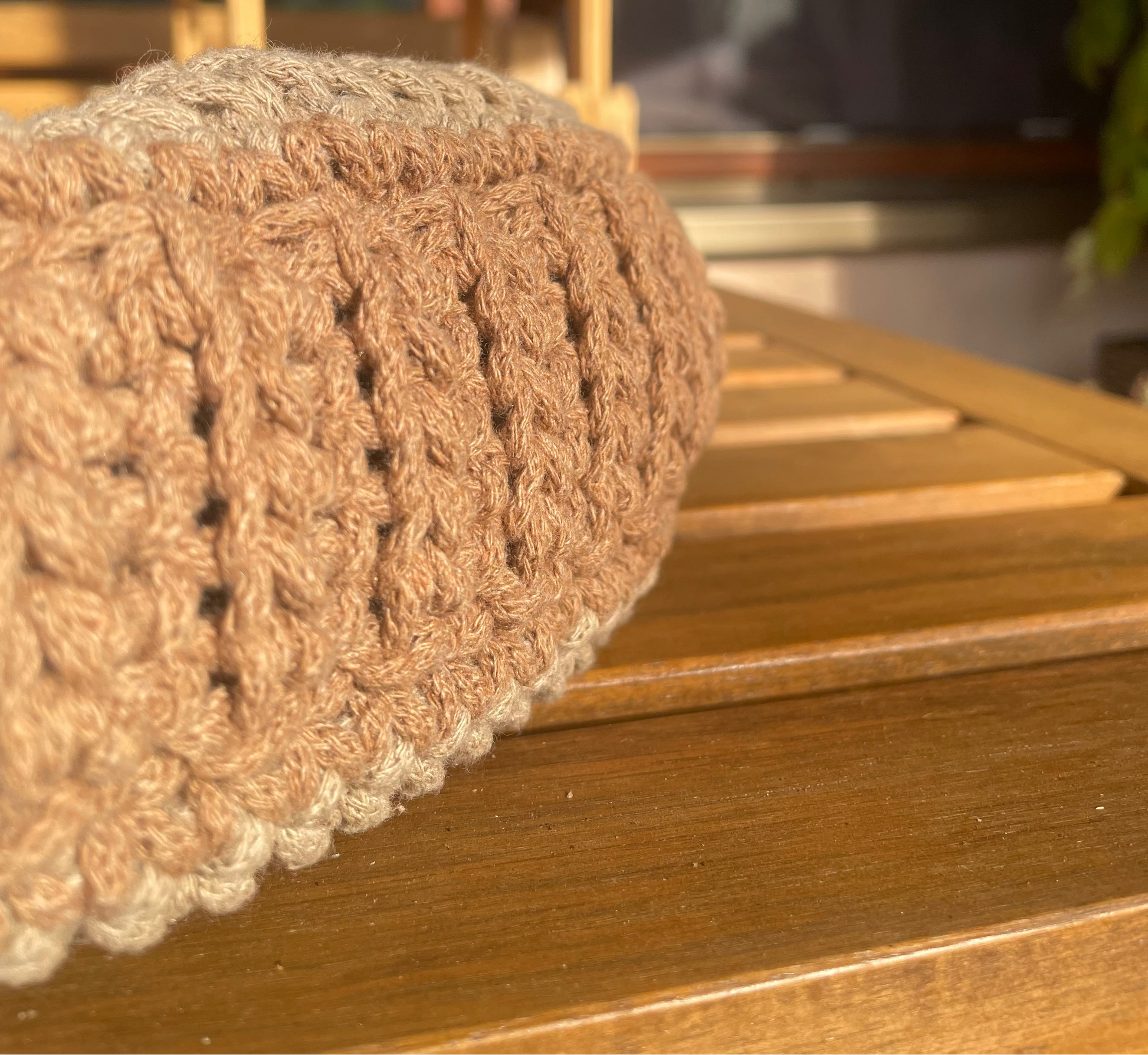 Nahaufnahme des Bodens der Tascche, der oben in den Umhängegurt übergeht. Tasche liegt auf der Seite auf einem Holztisch und wird von der Sonne beschienen.