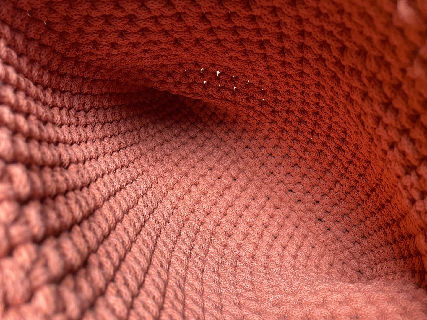 Detailansicht der FLORA Schultertasche aus gehäkeltem recyceltem Baumwollgarn in Terracotta-Orange. Das Foto zeigt das Innere der Tasche und daher die Textur und das Muster der Häkelarbeit sowie die sorgfältige Verarbeitung der handgefertigten Tasche.