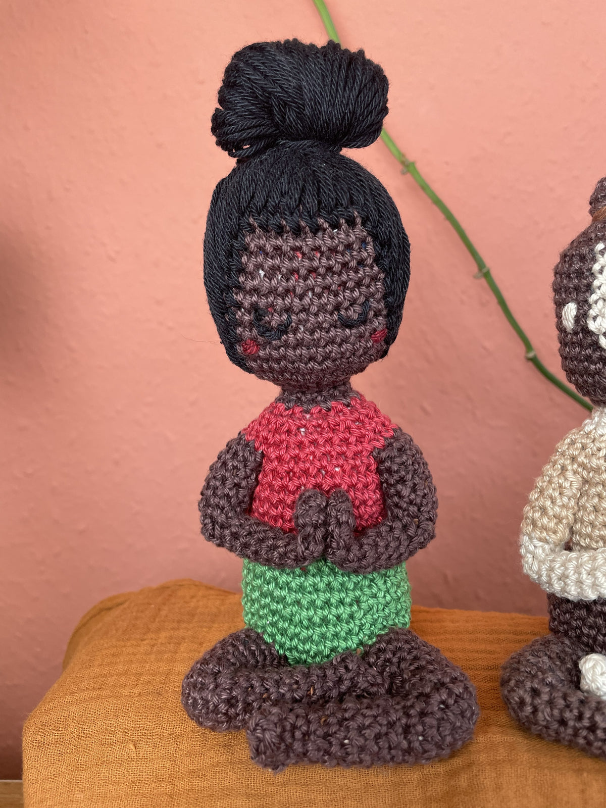 Weiblich-gelesene Figur, schwarzes Haar, dunkelbraune Hautfarbe, grasgrüne Shorts, rotes Shirt.